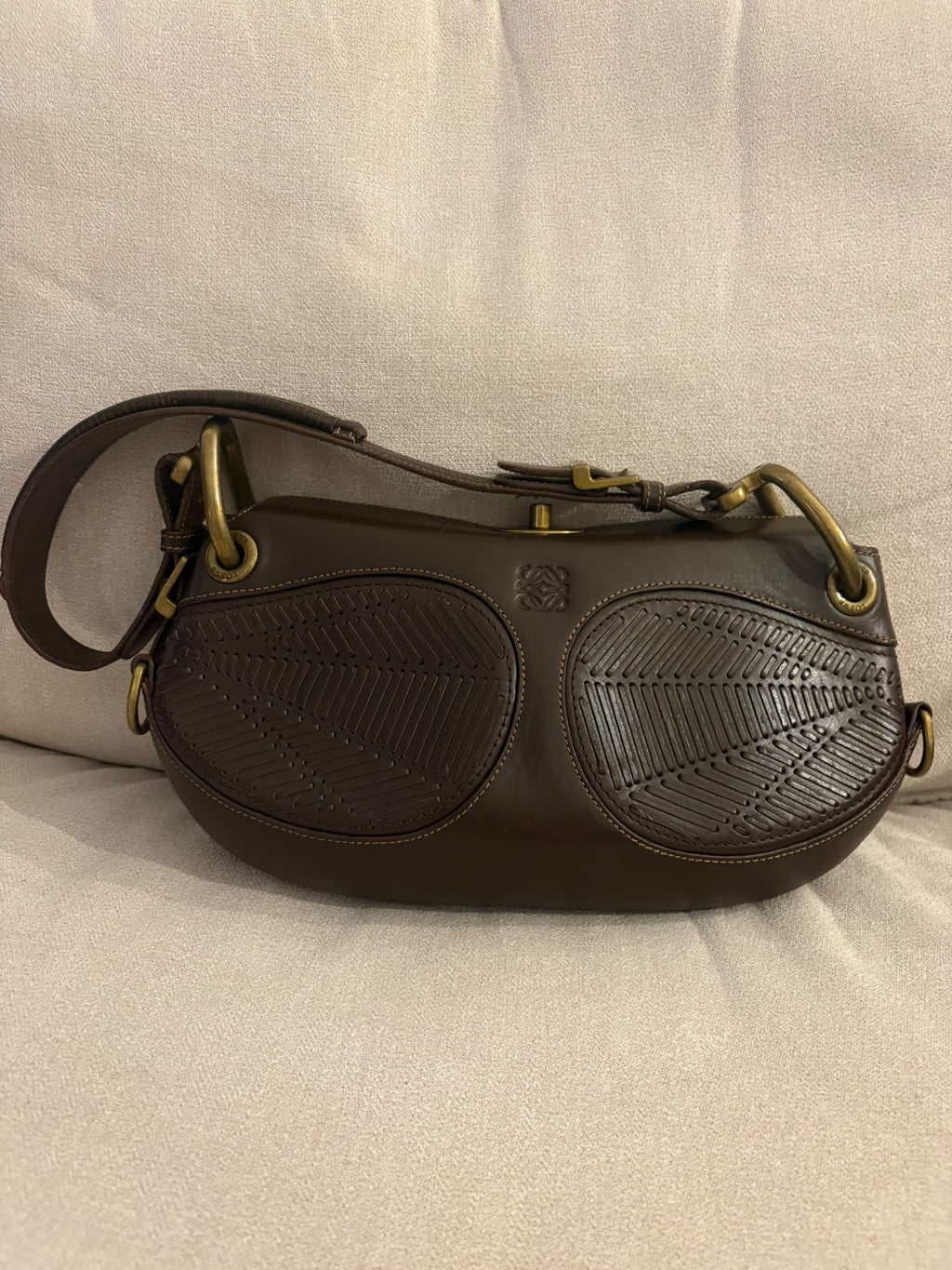 Loewe Turnlock con asa ajustable y paneles trenzados, vista frontal sobre asiento de tela
