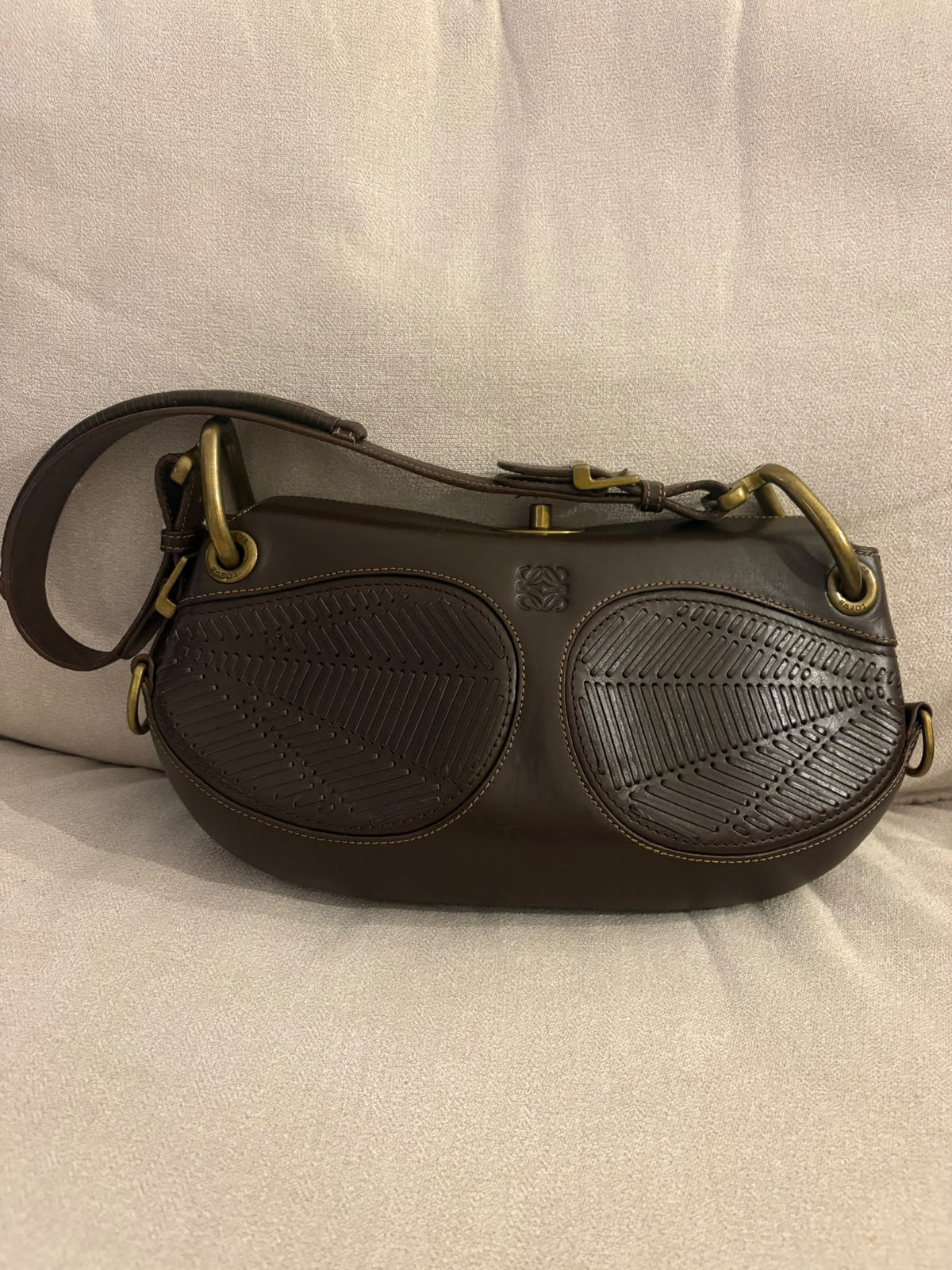 Loewe Turnlock con asa ajustable y paneles trenzados, vista frontal sobre asiento de tela