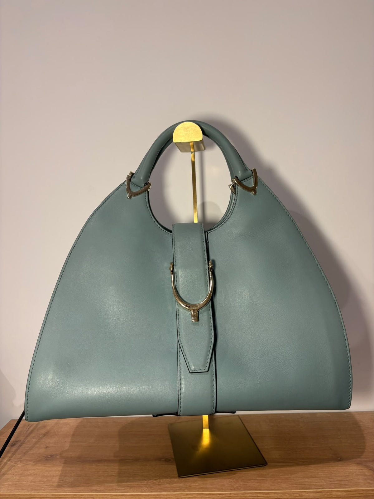 Gucci Stirrup con cierre frontal de estribo y herrajes dorados, vista frontal sobre soporte
