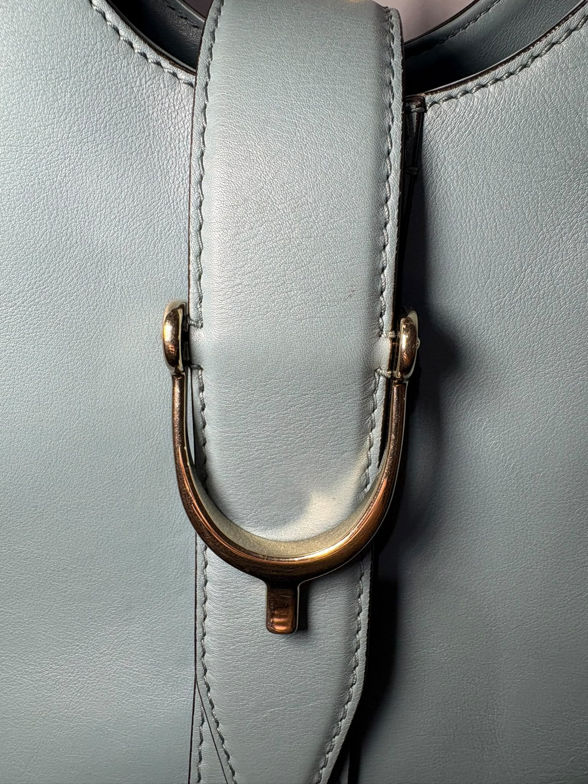 Gucci Stirrup, primer plano del cierre frontal de estribo dorado sobre la tira de piel